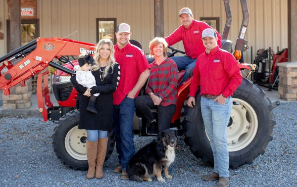 The Mathis family poses in front of a tractor